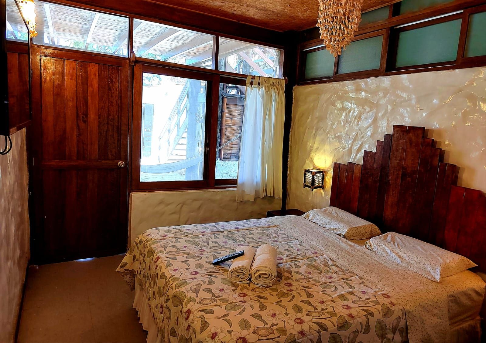 Un dormitorio con una cama grande, cabecera de madera y vistas al exterior por una ventana.