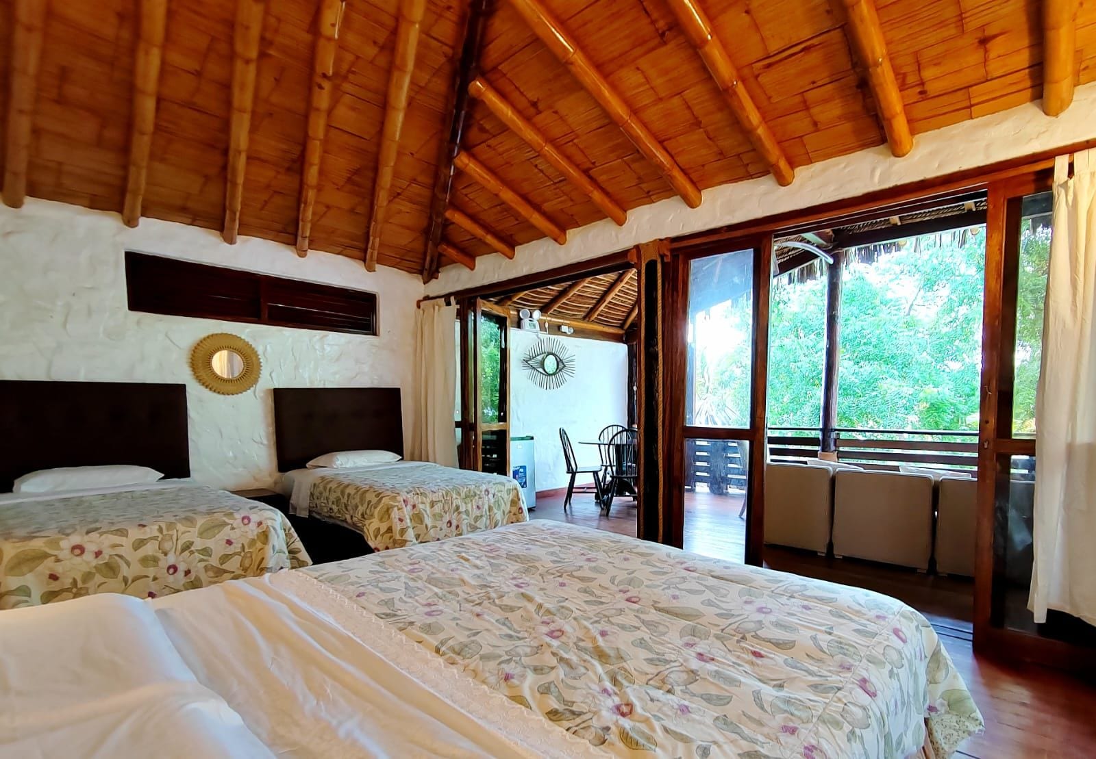 Habitación con dos camas, techo de madera y vista a zonas verdes.