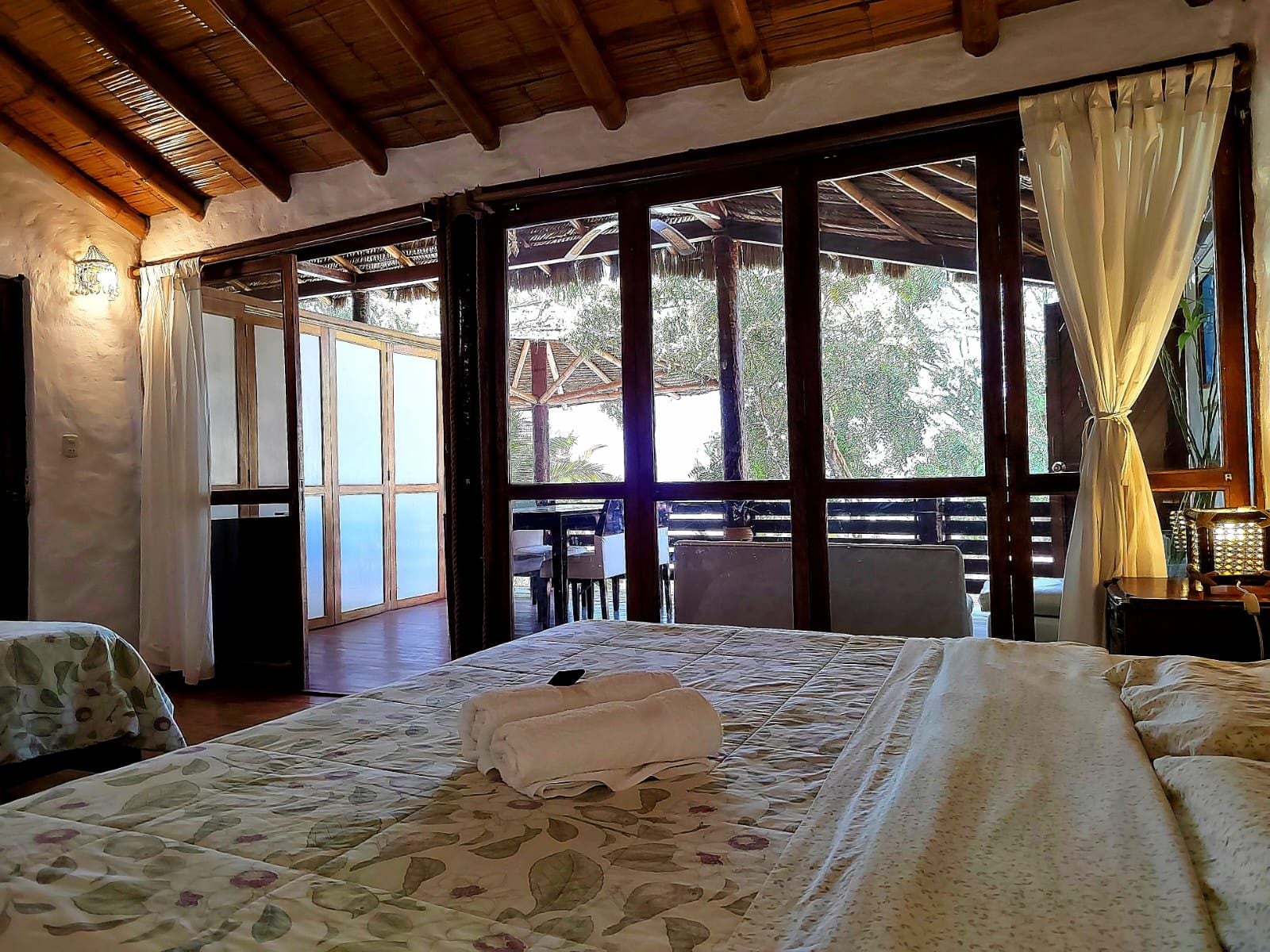 Una habitación con cama, una mesa y vistas al exterior a través de amplios ventanales.