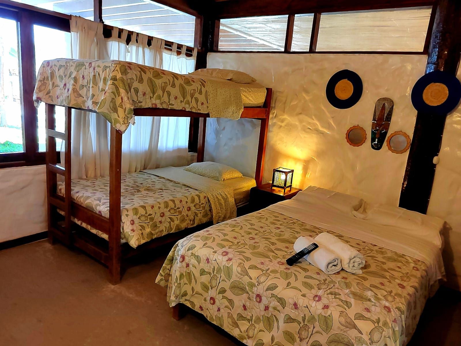 Una habitación con literas, una cama individual, una mesita de noche con lámpara y decoración en la pared.