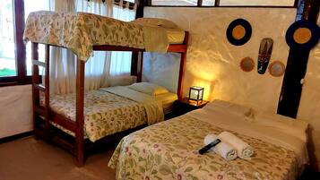 Una habitación con literas, una cama individual, una mesita de noche con lámpara y decoración en la pared.