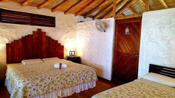 A room with a bed, a nightstand, a wall-mounted fan, and a wooden door.