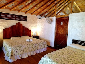 A room with a bed, a nightstand, a wall-mounted fan, and a wooden door.