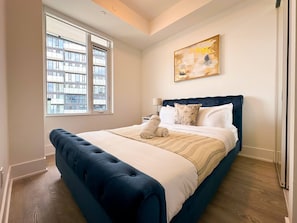 A bedroom with a large bed, a window, a painting, and a lamp. - Modern Downtown Toronto Retreat on Front Street (Toronto)