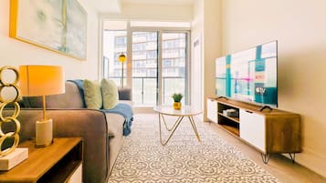 A modern living room with a sofa, a coffee table, a TV, and a large window.