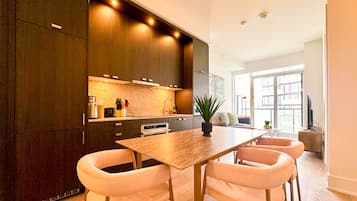 A modern kitchen with dark wood cabinets, a central island, and a dining area with white chairs.