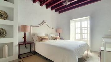Un dormitorio con cama, lámparas de noche, una ventana y una pared decorada con placas.