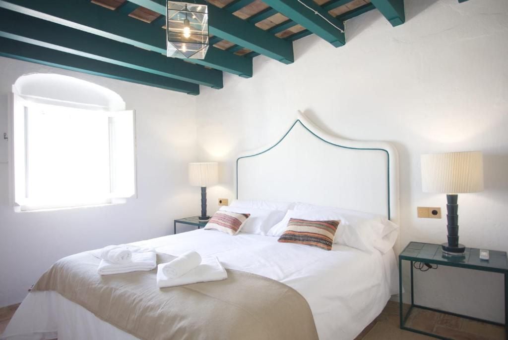 Quarto de hotel com uma cama, duas mesas de cabeceira, uma janela e teto com vigas aparentes.