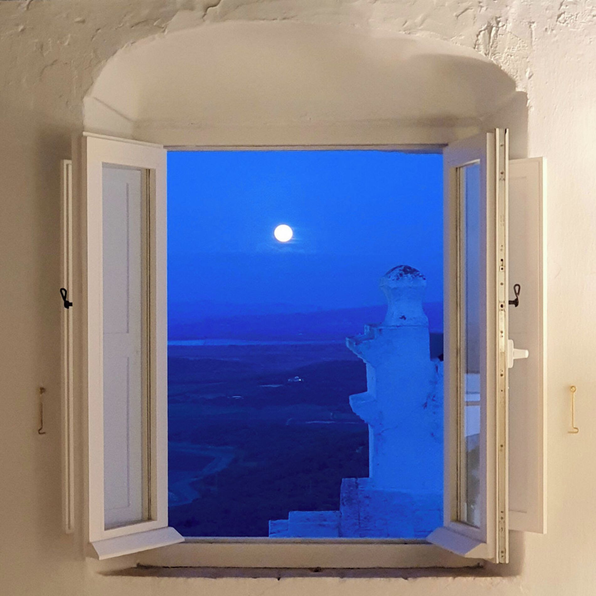 Una ventana con vistas a un paisaje iluminado por la luna y un faro.