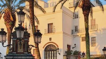 Una plaza con una fuente, palmeras y un edificio con balcones.