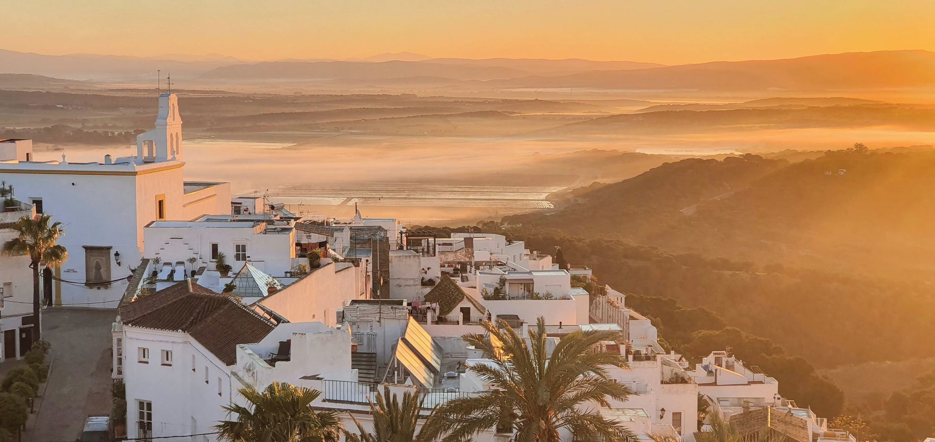 Un pueblo costero con edificios blancos, una iglesia y un río al fondo.