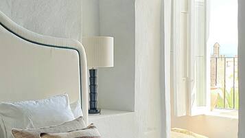 Un dormitorio con cama, almohadas, una lámpara y vistas al exterior.