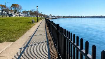 Eine Uferpromenade mit Betonweg, Bänken und Metallgeländer.
