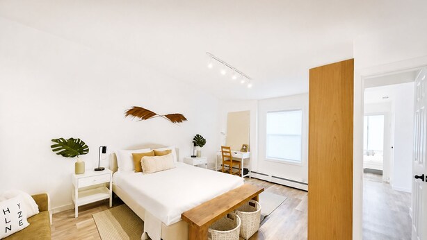 Une chambre moderne avec un grand lit, des tables de chevet, un bureau et un banc.