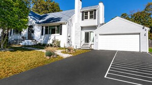 Une maison à deux étages avec un garage, un porche à l’avant et une allée menant au garage.