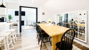 Une cuisine moderne avec des meubles blancs, une table à manger en bois et des chaises noires.
