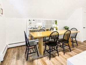 Un comedor con una mesa de madera y sillas negras, paredes blancas y una puerta blanca.