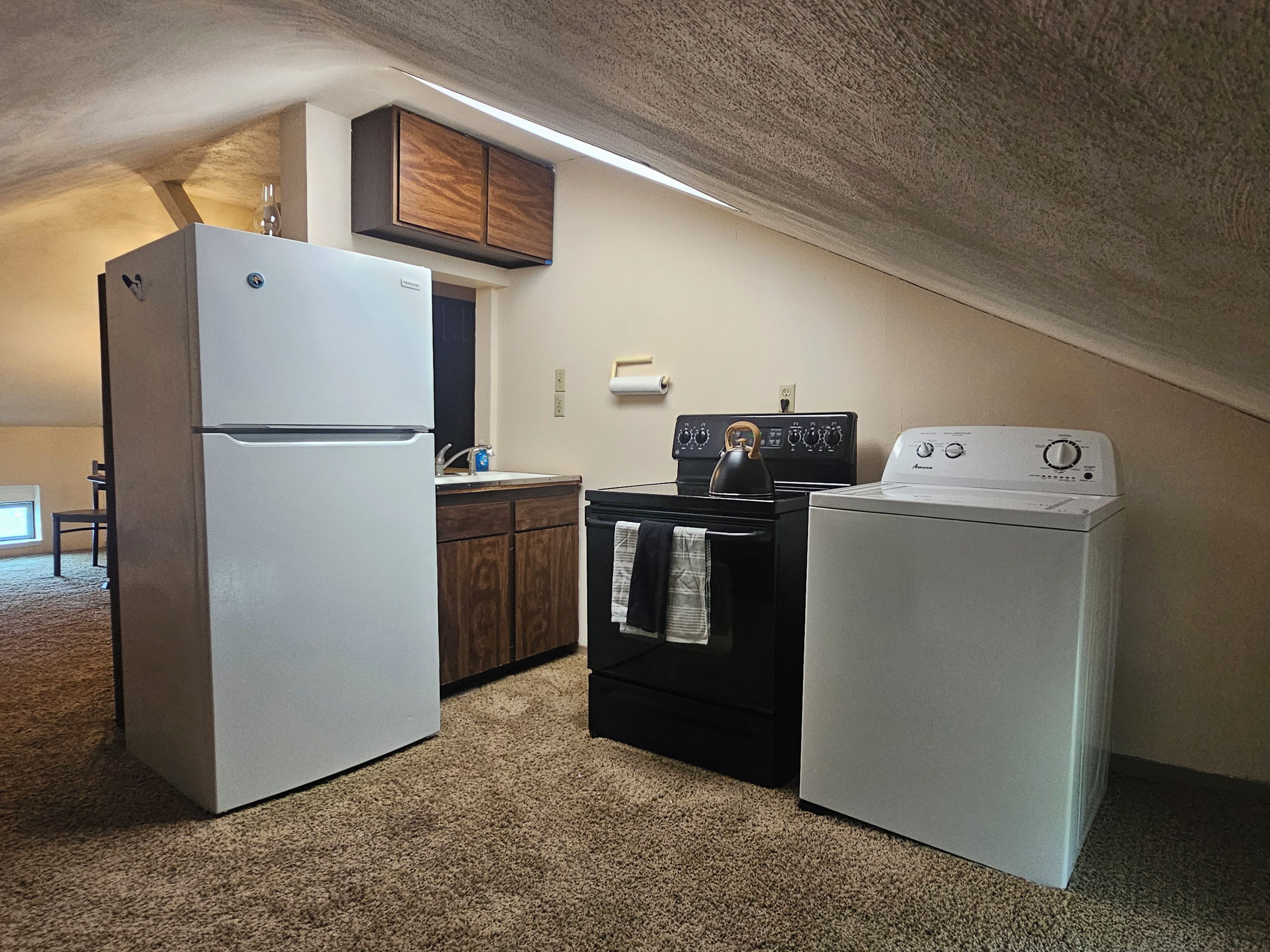 A compact kitchen with a refrigerator, stove, and washing machine.
