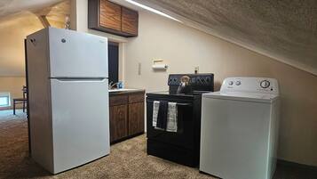 A compact kitchen with a refrigerator, stove, and washing machine.