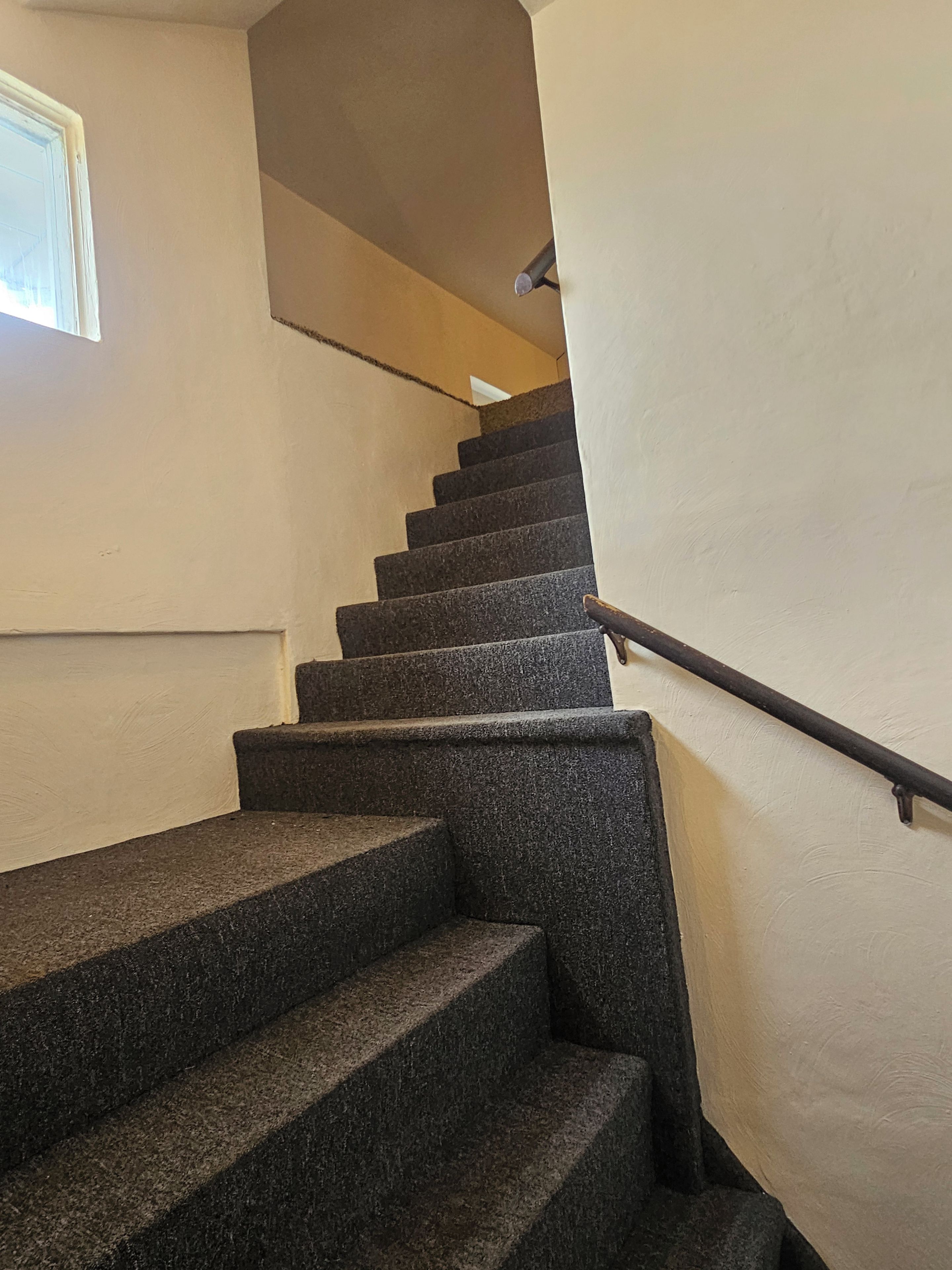 A staircase with a handrail, leading to an upper floor.