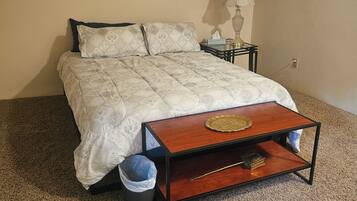 A bedroom with a bed, bedside table, lamp, and a small wooden table with a tray.