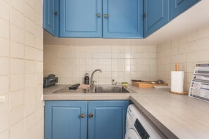 A kitchen with blue cabinets, a stainless steel sink, and a dishwasher. - South Kensington Period Retreat (London)