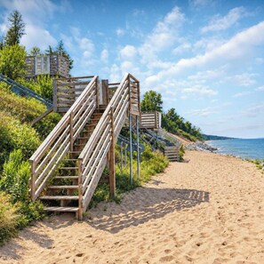 Wooden staircases leading to a beach with a clear sky. - Lake Breeze | Hot Tub | Steps to Lake Michigan! (South Haven)