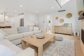 Een moderne woonkamer met een bank, salontafel, poef en een open haard.