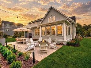 A two-story house with a patio area featuring outdoor furniture and a fire pit. - Lake Breeze | Hot Tub | Steps to Lake Michigan! (South Haven)