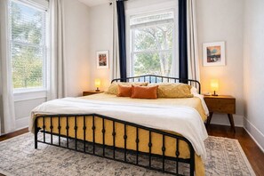 A bedroom with a bed, two bedside tables, a window with curtains, and a rug. - East Austin Gem, Cowboy Pool, Yard Games, Golf Put (Austin)