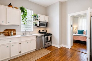 A modern kitchen with white cabinetry, a microwave, stove, and dishwasher. - East Austin Gem, Cowboy Pool, Yard Games, Golf Put (Austin)