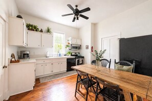 A compact kitchen with white cabinets, a wooden dining table, and a ceiling fan. - East Austin Gem, Cowboy Pool, Yard Games, Golf Put (Austin)