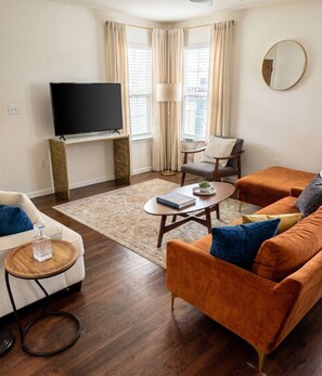 A living room with a flat-screen TV, two sofas, a coffee table, and a rug.