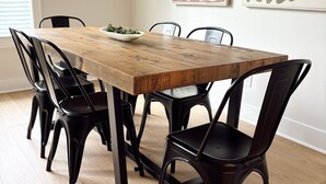Une table à manger avec six chaises, un saladier rempli de légumes verts et deux œuvres d’art abstraites accrochées au mur.