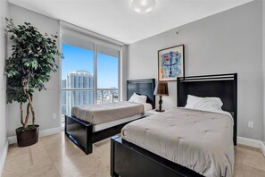 A hotel room with two beds, a large window with a city view, a potted plant, and a painting on the wall. - 2 Combined Corner Units! 4BR | Sleeps 10 (Miami)