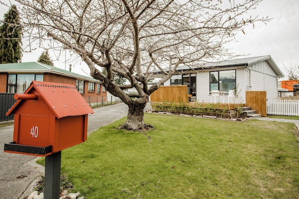 Ein Wohngebiet mit Briefkasten, Baum und einem modernen Haus mit Terrasse.