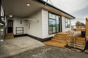 Ein Wohnhaus mit Veranda, einer Holztreppe und einem kleinen Garten.