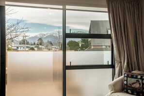 A room with a large window offering a view of a mountainous landscape and a residential area.