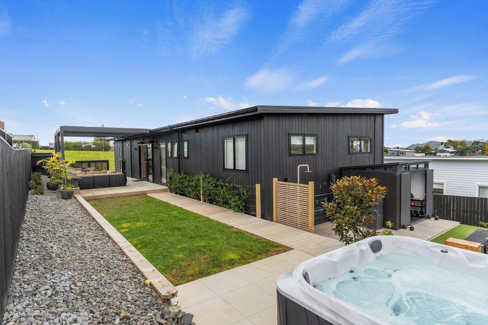 A modern house with a patio, a hot tub, and a small garden.