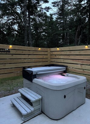 A hot tub with a wooden deck and steps, surrounded by a wooden fence and trees. - Ubuntu Haus • Near Castle Rock Lake • HOT TUB! (Friendship)