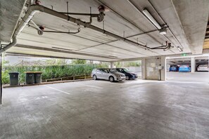 Eine Parkgarage mit Betonböden und Laufstegen, ein weißes Auto im Vordergrund und ein blaues Auto im Hintergrund.