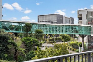 A pedestrian bridge with glass panels, surrounded by lush greenery and modern buildings. - Westlight Apartment - Henderson Holiday Home (Henderson)