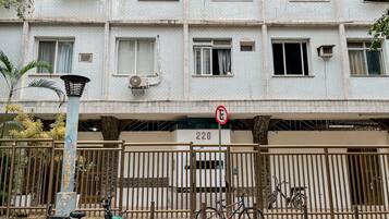 A multi-story residential building with a gated entrance, numbered 228, and a no-parking sign.