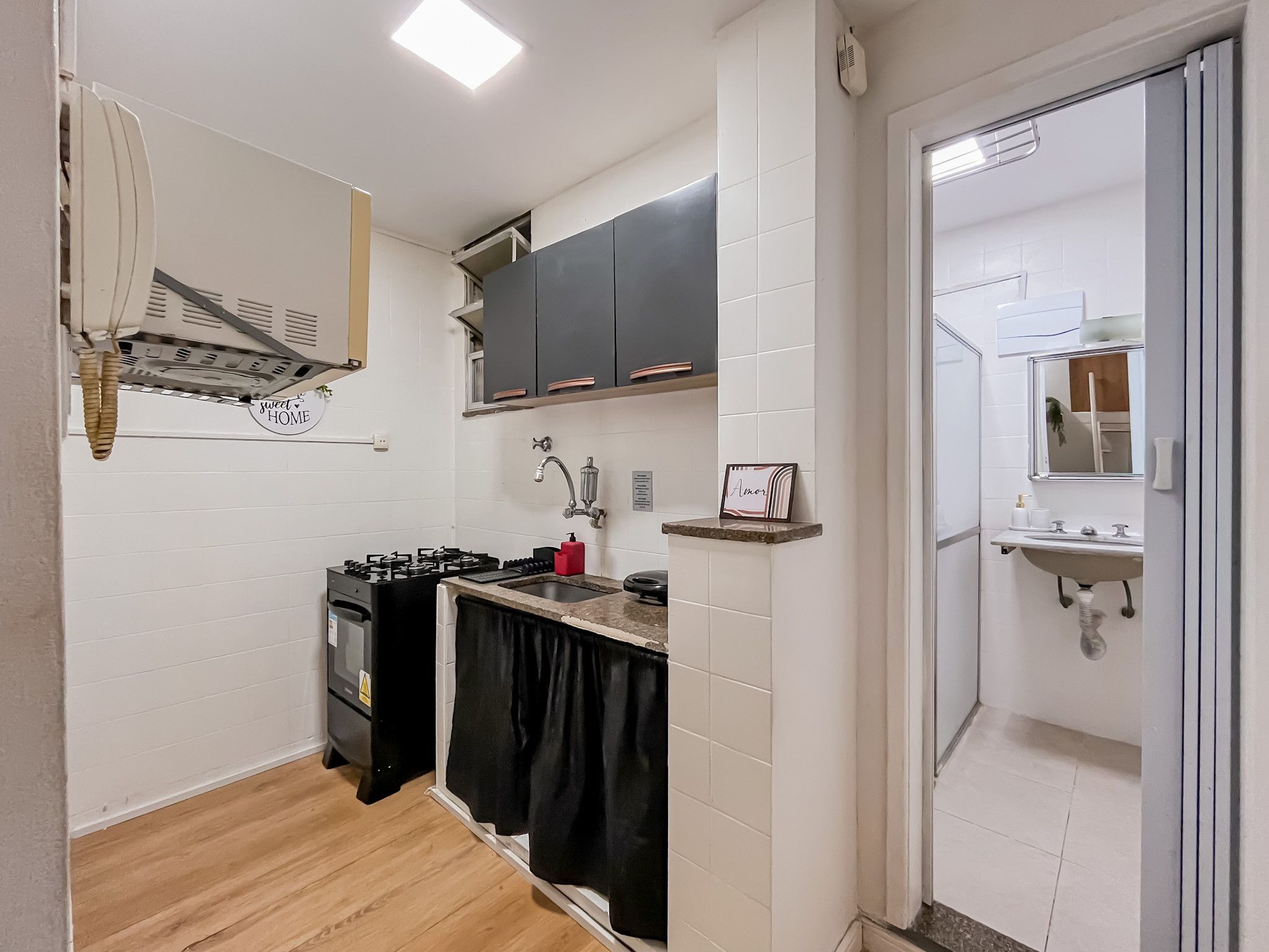 A compact kitchen with a gas stove, black cabinets, and a white tiled backsplash.