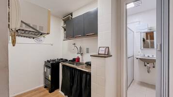 A compact kitchen with a gas stove, black cabinets, and a white tiled backsplash.