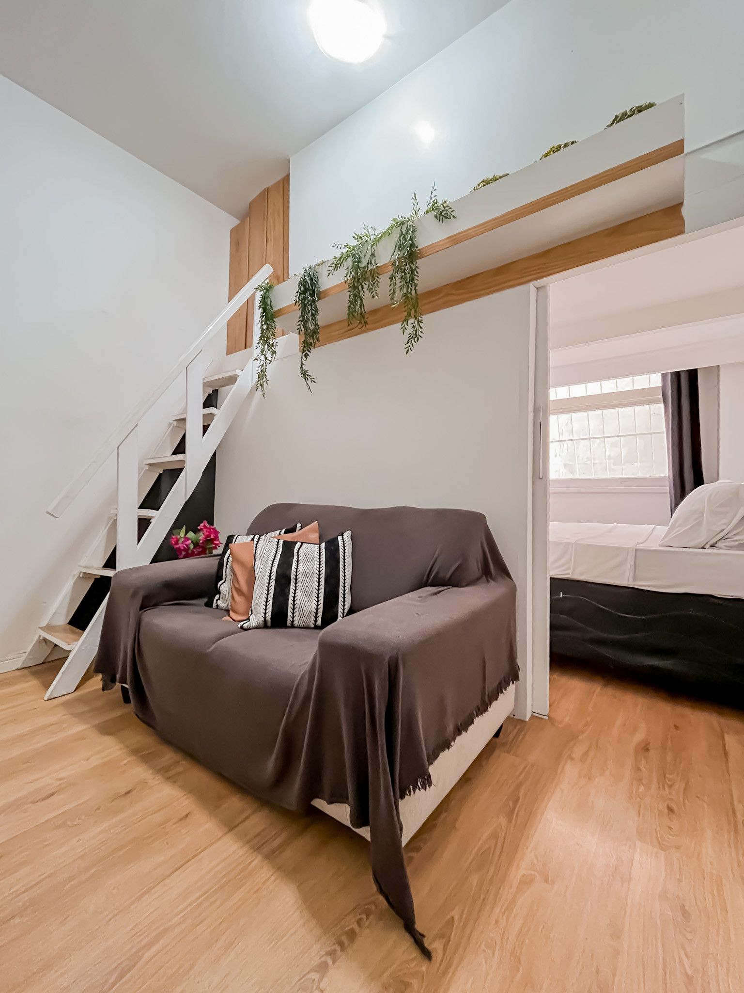 A modern living space with a sofa, a staircase, and a bed.