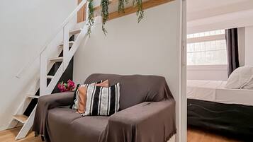 A modern living space with a sofa, a staircase, and a bed.