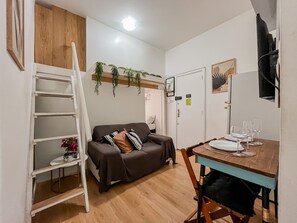 A compact living space with a sofa, a dining table set for two, a ladder, and a small shelf with a plant. - Charming Apartment 5 Min From Copacabana Beach - Sf415 (Rio de Janeiro)