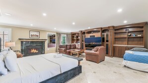 Una sala de estar amplia con chimenea, una cama grande, un sofá y un televisor.