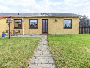 A single-story brick house with a tiled roof, a front door, and a small porch with chairs. - 4 Person Holiday Home in Bindslev (Bindslev)